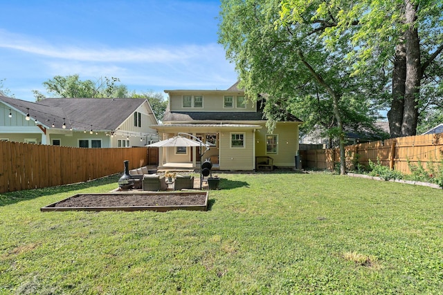 back of house featuring a yard, an outdoor living space, and a fenced backyard