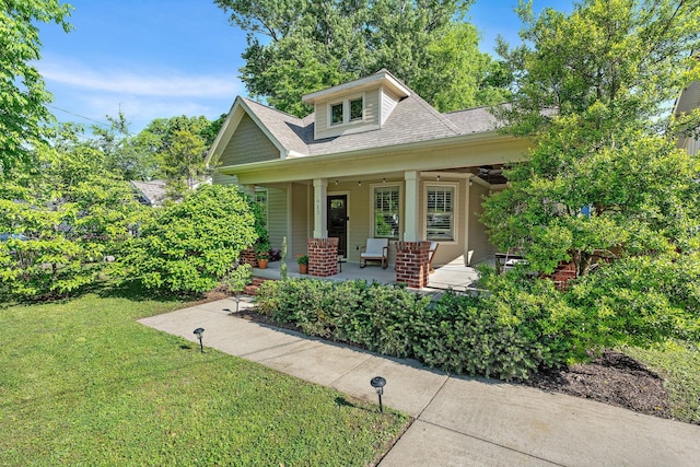 view of front of house with roof with shingles, a porch, and a front yard