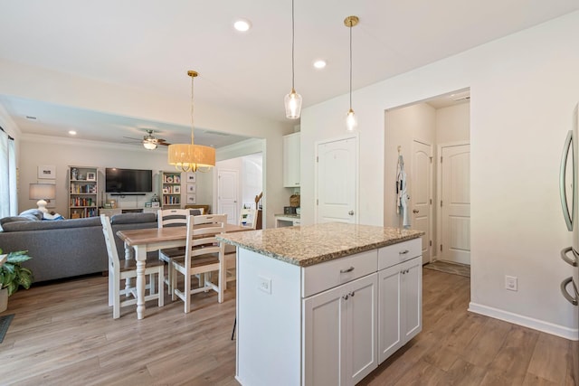 kitchen featuring white cabinetry, open floor plan, light wood finished floors, and ceiling fan with notable chandelier