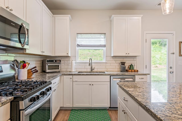 kitchen featuring white cabinetry, a sink, a toaster, stainless steel appliances, and light wood-style flooring