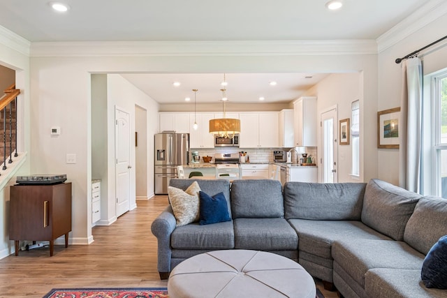 living room featuring ornamental molding, baseboards, stairway, recessed lighting, and light wood finished floors