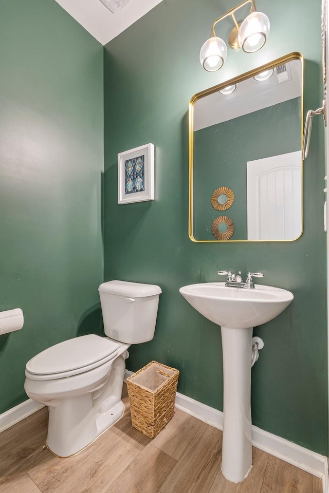 bathroom with toilet, baseboards, and wood finished floors