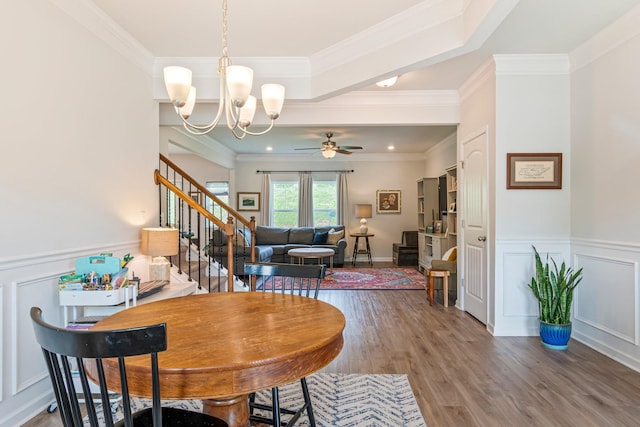 dining space with ornamental molding, ceiling fan with notable chandelier, and wood finished floors