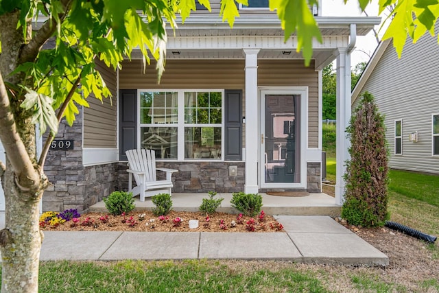 doorway to property with a porch and stone siding