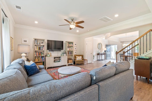 living area with stairway, ceiling fan with notable chandelier, light wood-style flooring, and visible vents