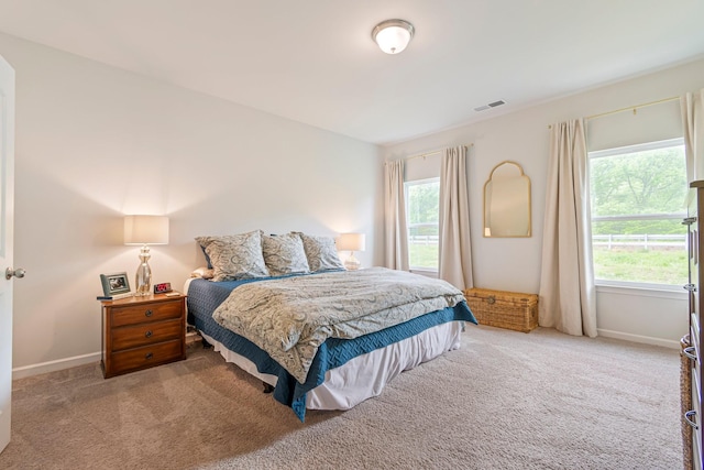 carpeted bedroom featuring visible vents, baseboards, and multiple windows