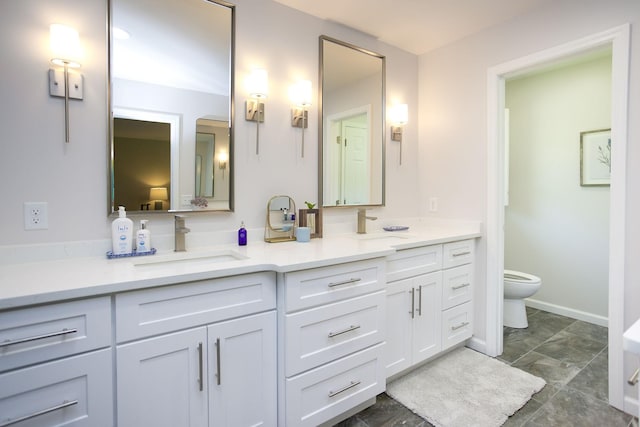 bathroom with double vanity, a sink, baseboards, and toilet