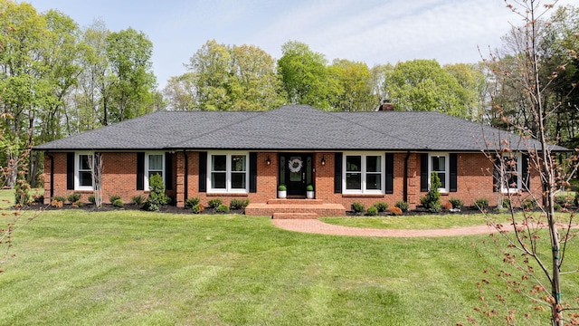 ranch-style house with brick siding, a chimney, a shingled roof, and a front yard