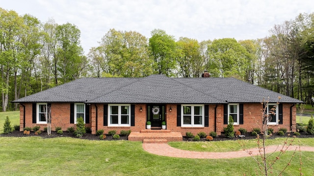 ranch-style house with a shingled roof, a chimney, a front lawn, and brick siding