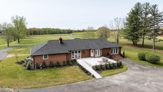 view of front of home with french doors, a chimney, a patio area, brick siding, and a front lawn