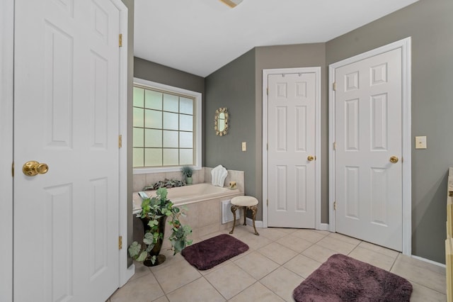 bathroom with tile patterned floors, baseboards, and a bath