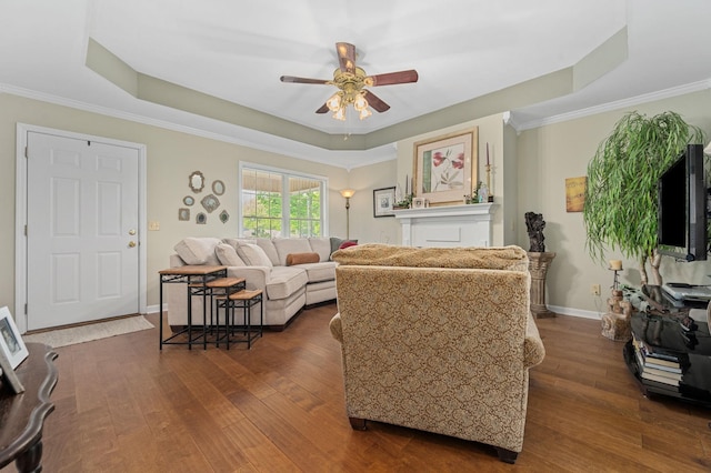 living area featuring crown molding, a ceiling fan, dark wood finished floors, and a raised ceiling