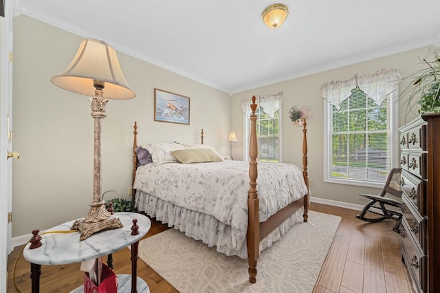bedroom with crown molding, baseboards, and wood finished floors