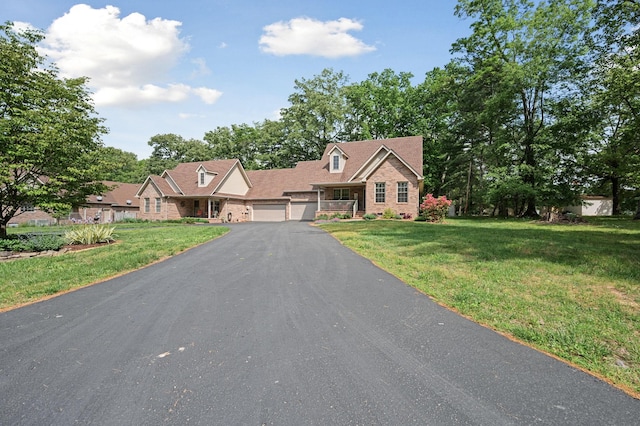 cape cod house featuring an attached garage, driveway, and a front yard