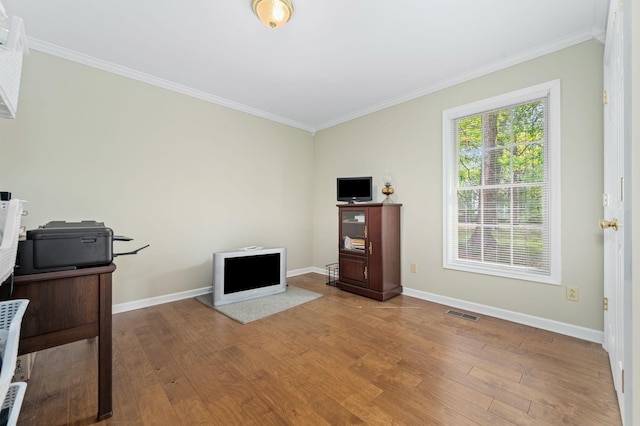 interior space with baseboards, ornamental molding, and wood finished floors