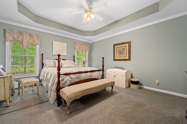 carpeted bedroom featuring a ceiling fan, a tray ceiling, ornamental molding, and baseboards