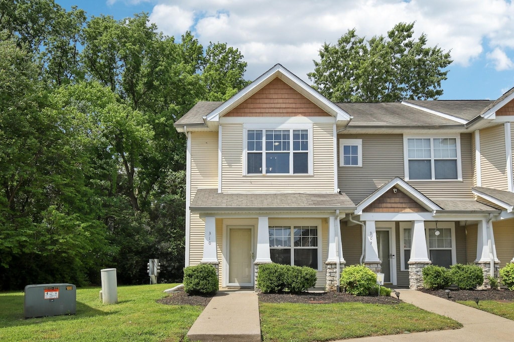craftsman inspired home featuring a front lawn, roof with shingles, and covered porch