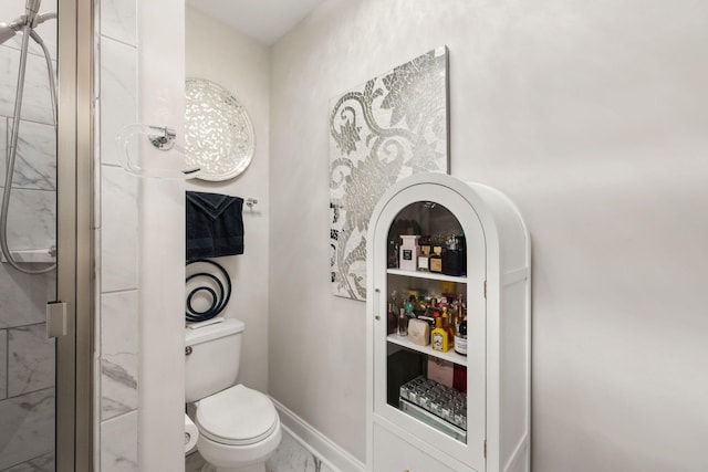 bathroom with baseboards, toilet, a shower, and marble finish floor