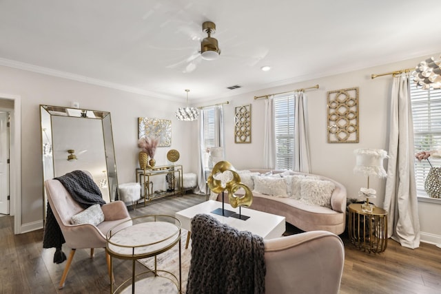 living area featuring crown molding, visible vents, wood finished floors, and ceiling fan with notable chandelier
