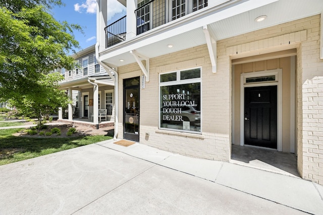 entrance to property featuring brick siding, a patio area, and a balcony