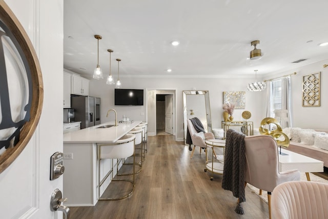 interior space featuring white cabinets, stainless steel fridge, a sink, a breakfast bar area, and visible vents