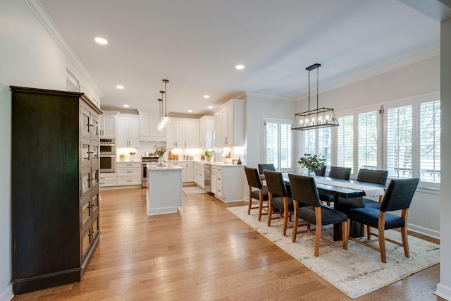 dining room with recessed lighting, an inviting chandelier, ornamental molding, and light wood-type flooring