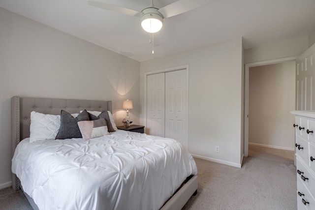 bedroom with baseboards, ceiling fan, light carpet, and a closet