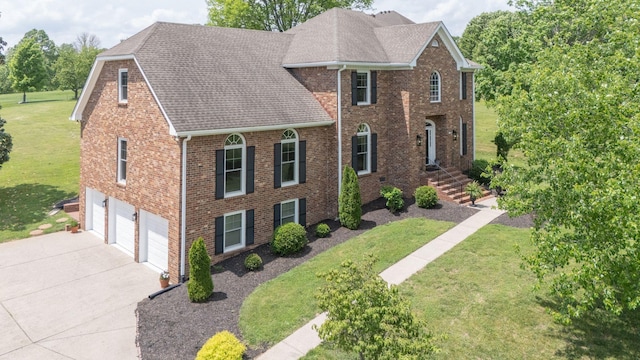 traditional-style house featuring brick siding, a garage, a front yard, and concrete driveway