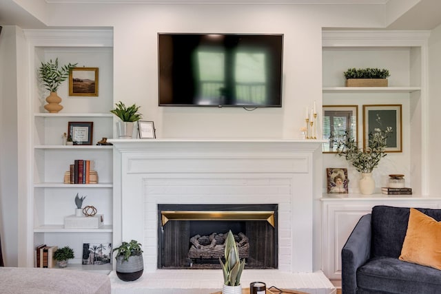 living room featuring a brick fireplace and built in shelves
