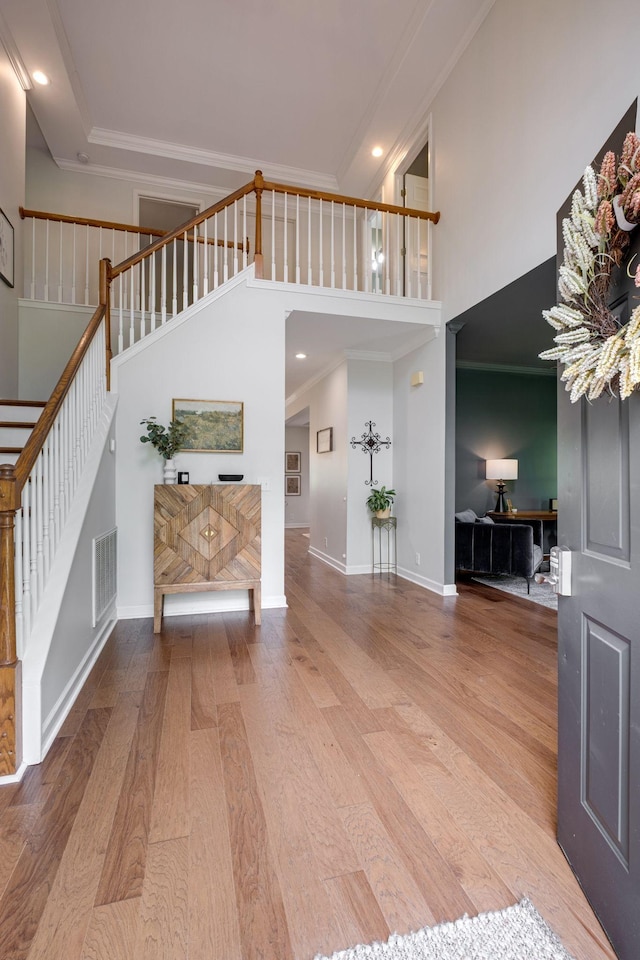 entryway featuring stairway, visible vents, wood finished floors, and a towering ceiling