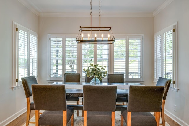 dining space featuring an inviting chandelier, ornamental molding, baseboards, and wood finished floors