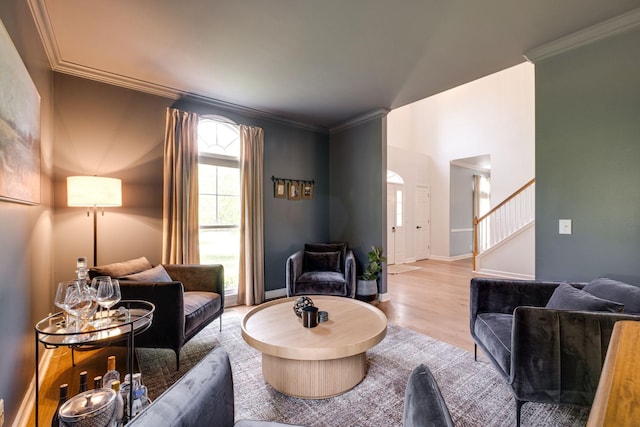 living area featuring crown molding, baseboards, stairway, and wood finished floors