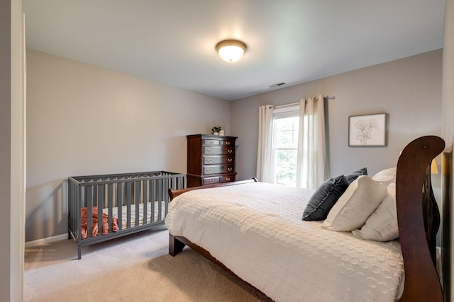 bedroom with baseboards, visible vents, and light carpet
