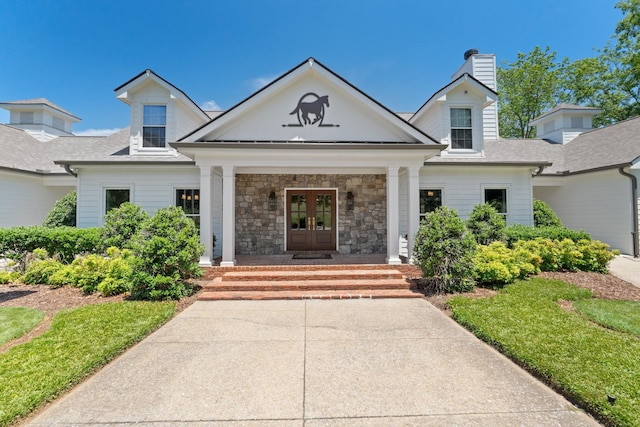 exterior space featuring a porch, french doors, a chimney, a shingled roof, and stone siding