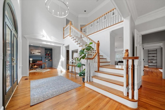 entryway featuring baseboards, wood finished floors, a towering ceiling, ornamental molding, and stairway