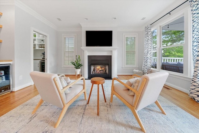 living area featuring crown molding, baseboards, a fireplace with flush hearth, and wood finished floors