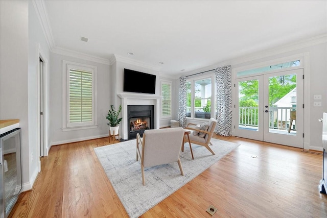 living area with a fireplace with flush hearth, wine cooler, a healthy amount of sunlight, and ornamental molding