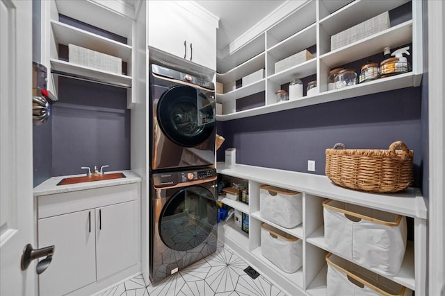 clothes washing area with a sink, cabinet space, and stacked washer / dryer