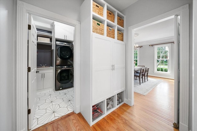 mudroom with a chandelier, stacked washing maching and dryer, a sink, and light wood finished floors
