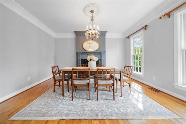 dining area featuring an inviting chandelier, ornamental molding, wood finished floors, and visible vents