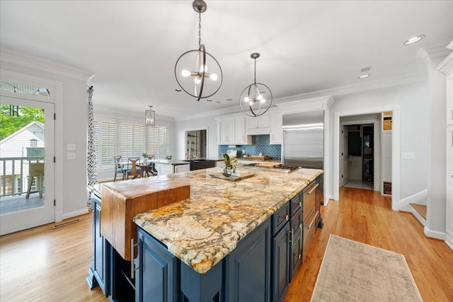 kitchen featuring a kitchen island, blue cabinets, white cabinets, a notable chandelier, and light wood-style flooring