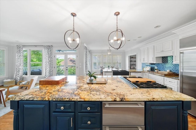 kitchen with stainless steel appliances, blue cabinets, white cabinetry, and a chandelier