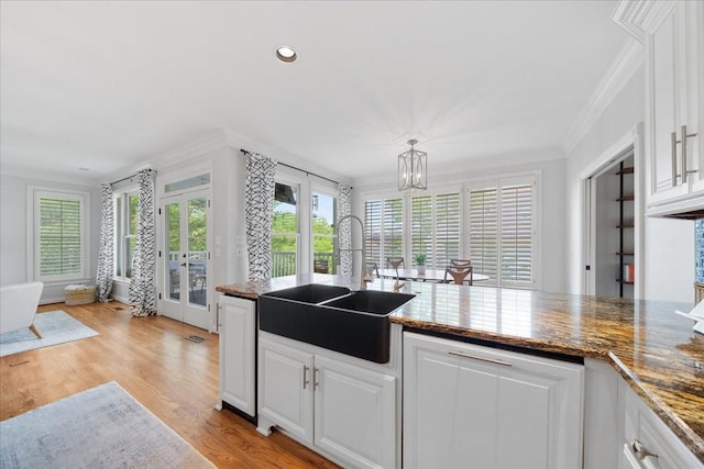 kitchen with french doors, crown molding, a sink, white cabinets, and a notable chandelier