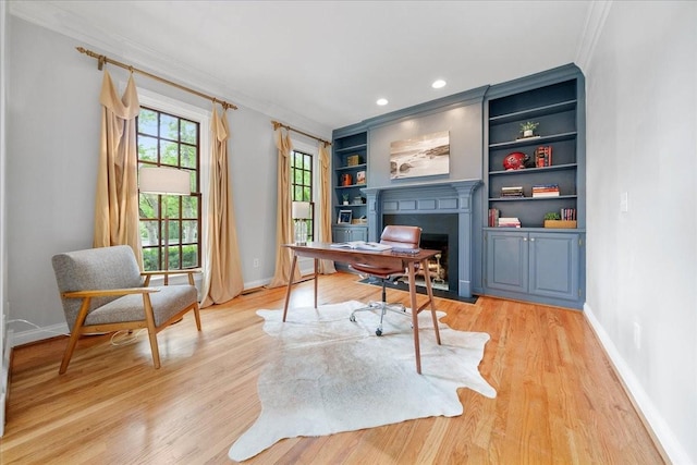 office area with a fireplace with flush hearth, baseboards, ornamental molding, and light wood finished floors