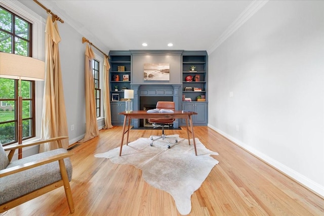 home office with crown molding, baseboards, built in shelves, and light wood-type flooring