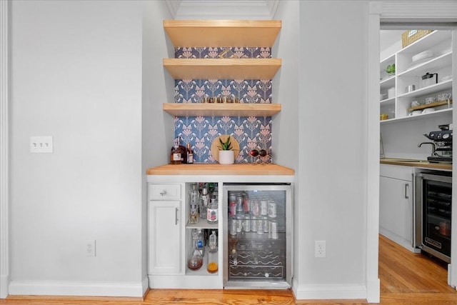 bar with wine cooler, a dry bar, and light wood-type flooring