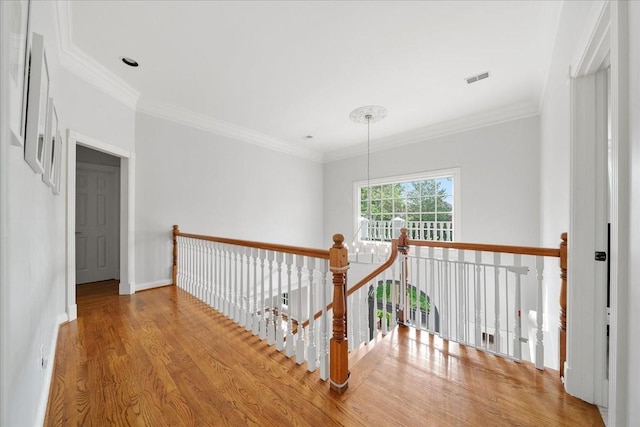 corridor featuring crown molding, baseboards, an upstairs landing, wood finished floors, and visible vents