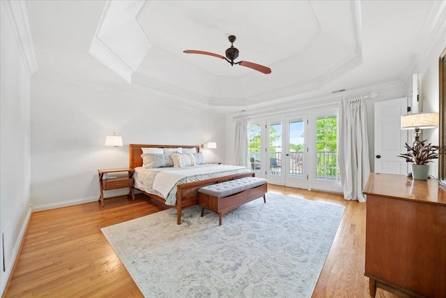 bedroom with crown molding, access to outside, light wood-style flooring, and a raised ceiling