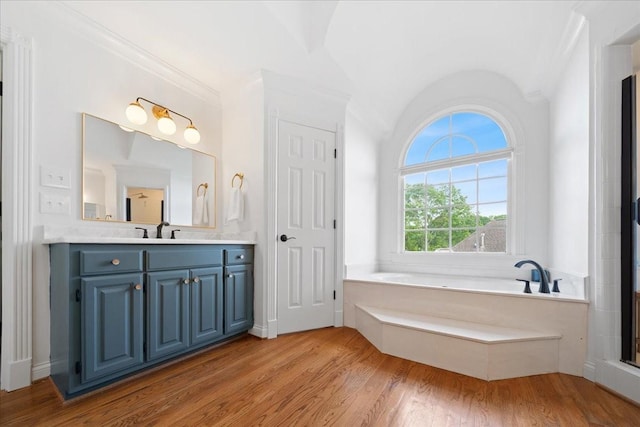 bathroom featuring vanity, a bath, lofted ceiling, and wood finished floors