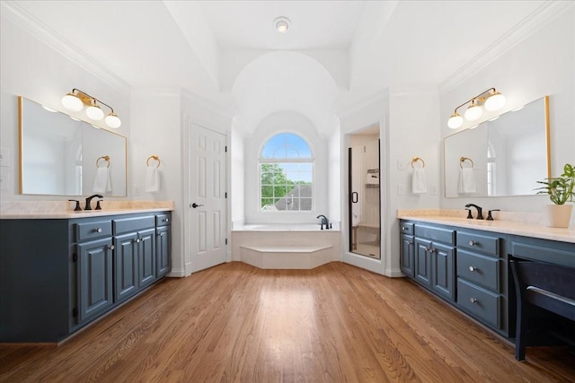full bath featuring a garden tub, a sink, wood finished floors, and two vanities
